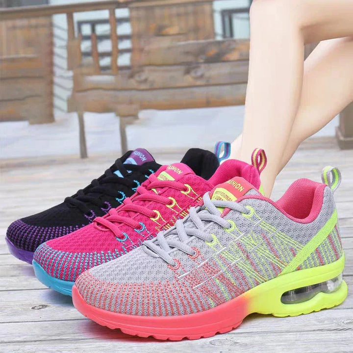Colorful women's fashion sneakers in gray with neon accents, pink, and black displayed outdoors