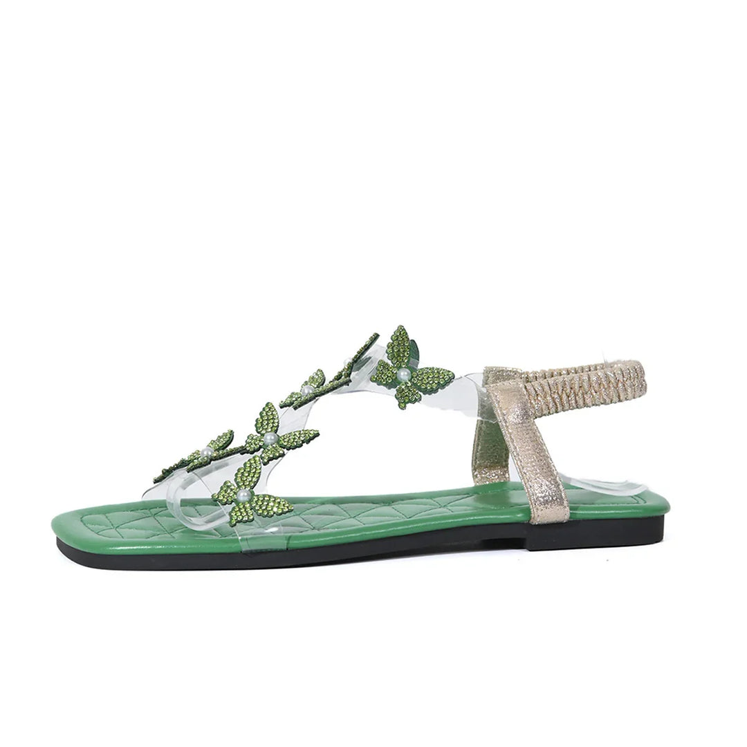 Green flat sandal with transparent straps decorated with green rhinestone butterflies and gold elastic back strap