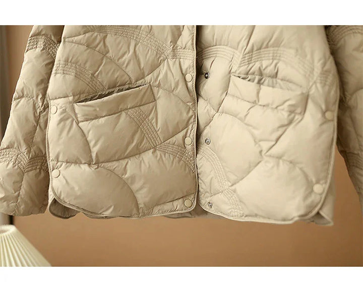 Beige quilted jacket with distinctive stitching and snap button closures, front pockets visible