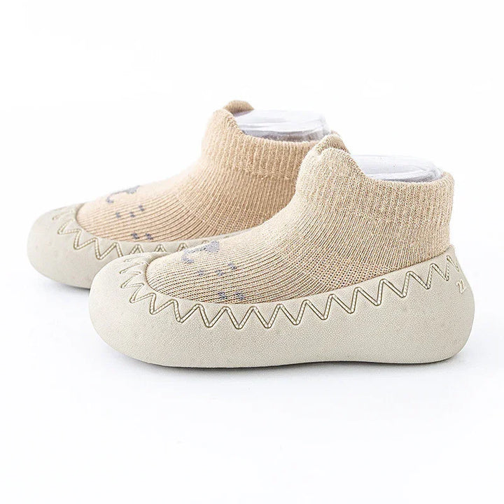 Beige toddler soft sole shoes with knitted sock ankle and zigzag stitching on white background