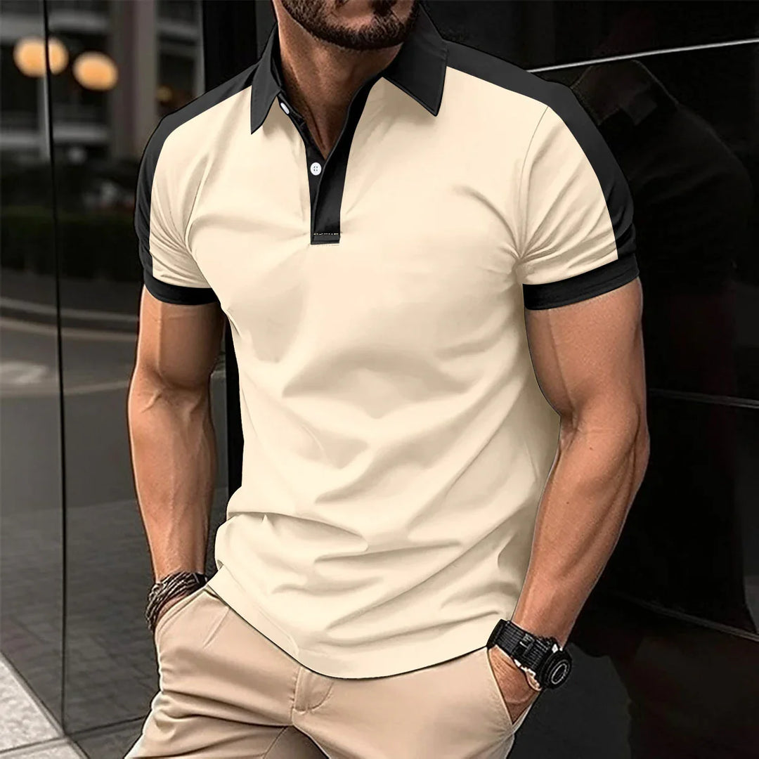 Man wearing beige and black short-sleeve polo shirt with beige pants, standing outdoors