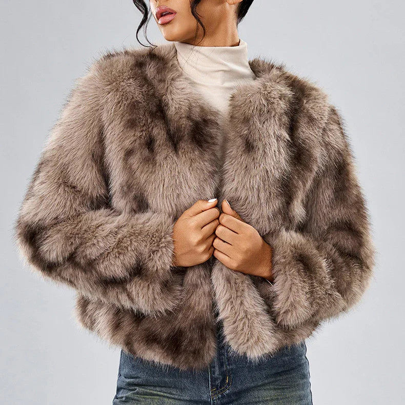 Woman wearing a plush taupe faux fur jacket over white turtleneck and blue jeans