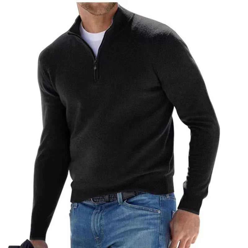 Man wearing black quarter zip sweater over white shirt with blue jeans on white background