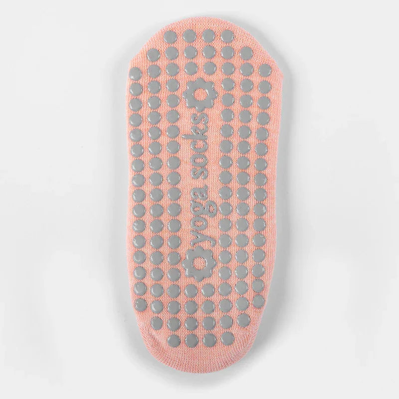 Pink yoga sock with non-slip gray dots and 'yoga socks' text on the sole