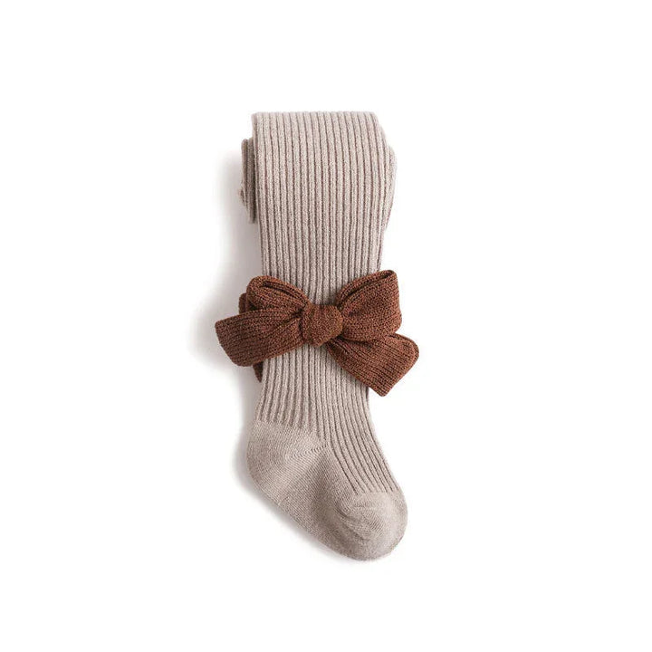 Beige ribbed knit tights with a large brown knit bow accessory on white background