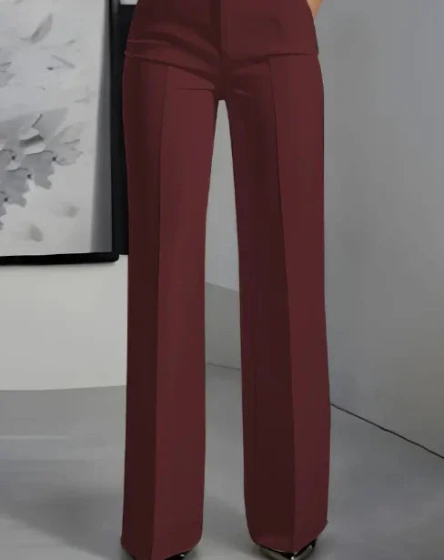 Close-up of high-waisted, wide-leg burgundy dress pants worn by a model in a modern indoor setting
