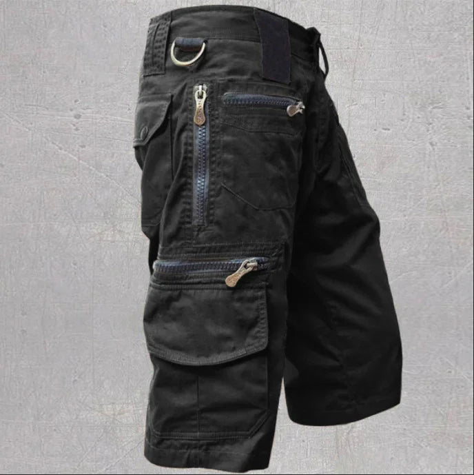 Black cargo shorts with multiple zipped and flap pockets and a metal ring on the waistband