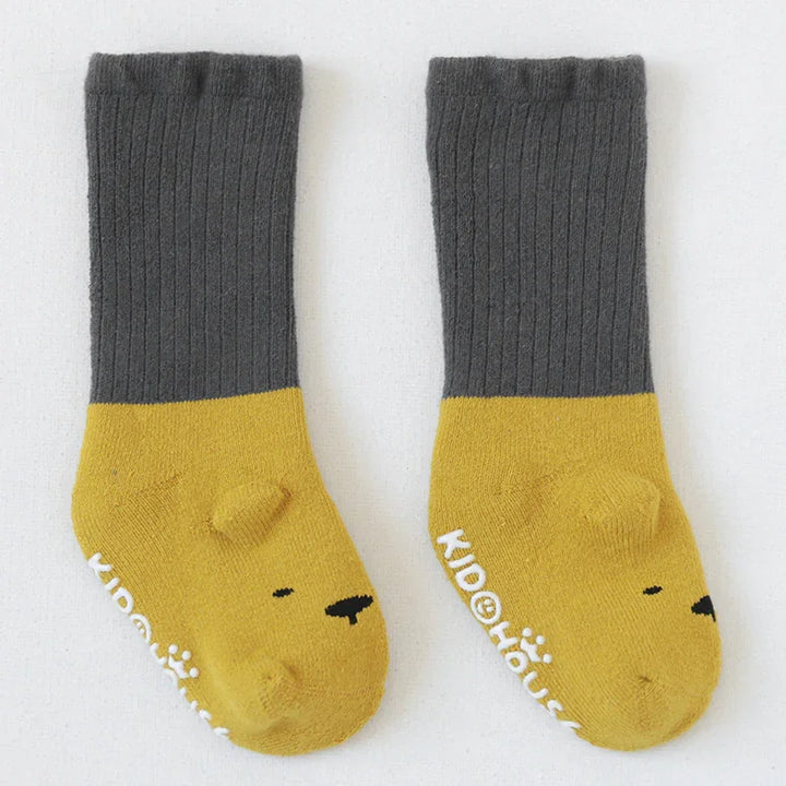 Pair of gray and yellow children's socks with bear face design and non-slip white text soles