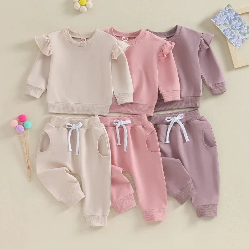 Three sets of baby girl ruffle sleeve sweatshirts and jogger pants in beige, pink, and mauve colors