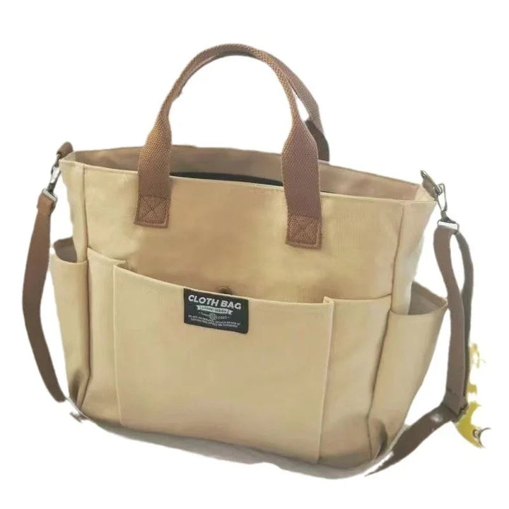 Beige cloth tote bag with brown handles, front pocket, and detachable shoulder strap