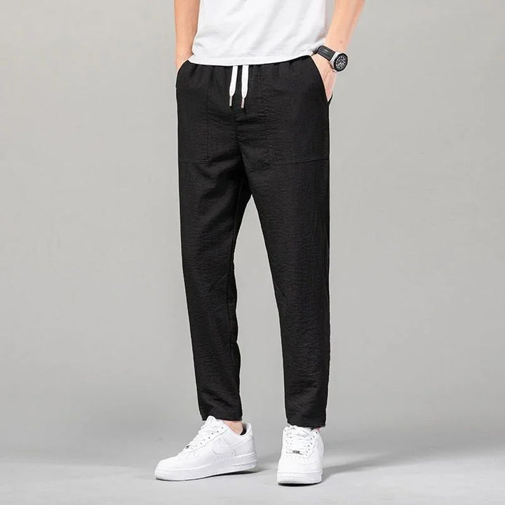 Men's casual black jogger pants with white drawstring, paired with white sneakers and a white t-shirt
