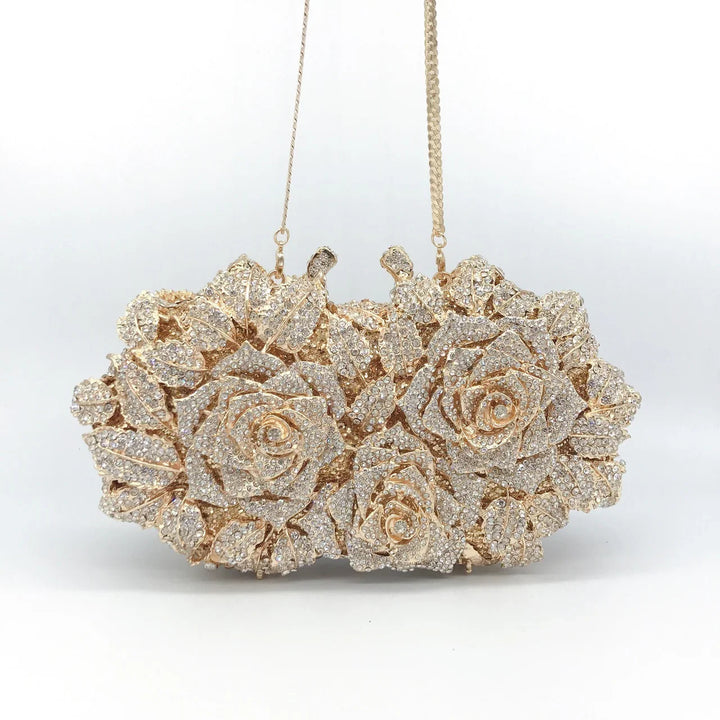 Gold clutch bag embellished with sparkling rhinestone roses and leaves, featuring a chain strap