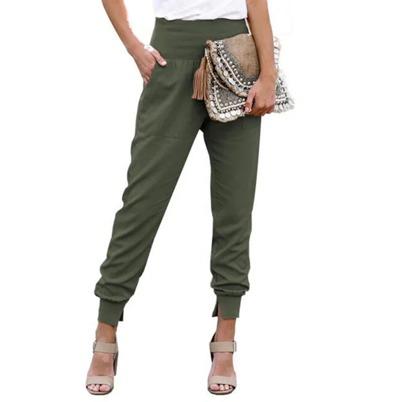 Woman wearing olive green jogger pants and beige high heel sandals holding a decorative clutch bag