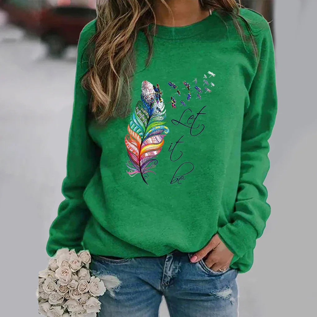 Green sweatshirt with colorful feather and dragonfly design and Let it be text, worn with blue jeans