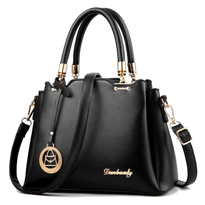 Black leather handbag with gold hardware, double top handles, adjustable shoulder strap, and decorative logo charm