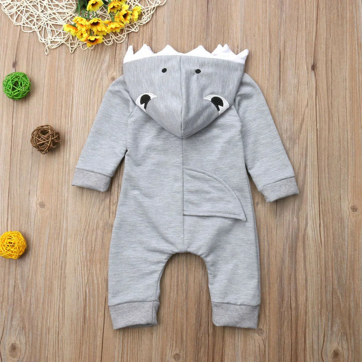 Gray baby onesie with hood featuring dinosaur spikes, eyes, and tail on wooden background