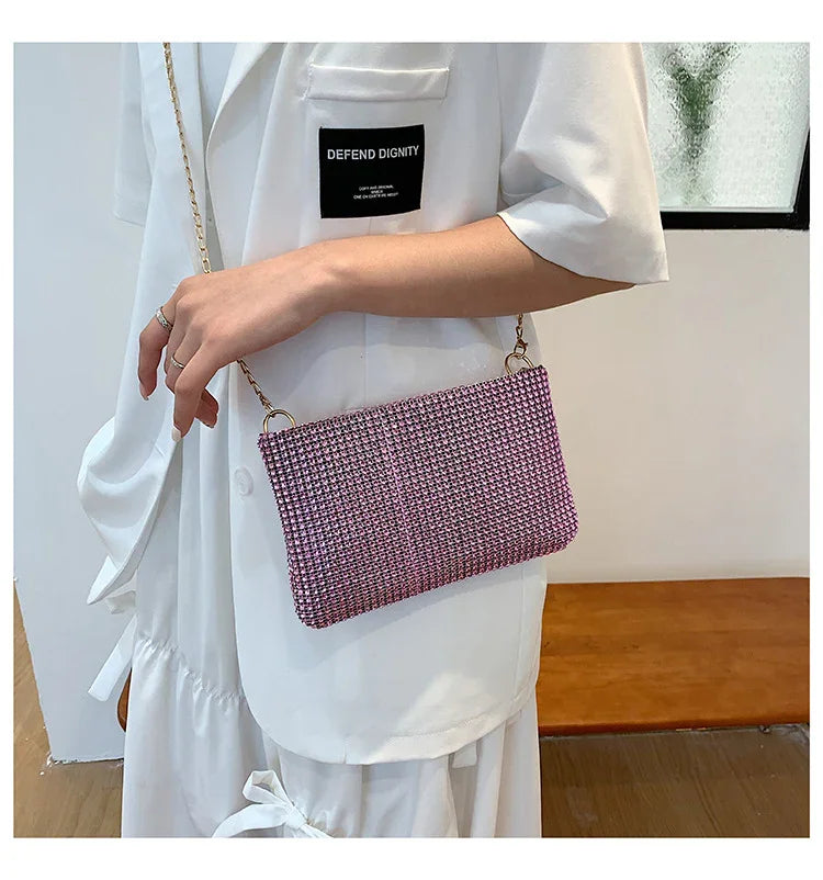 Woman wearing white outfit with black 'Defend Dignity' patch holding pink woven crossbody bag with gold chain strap