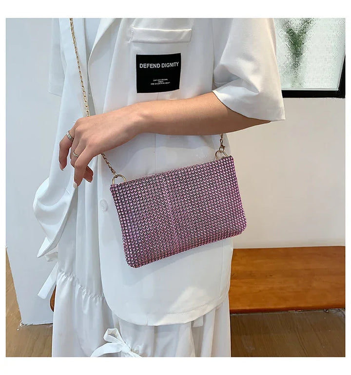 Woman wearing white outfit with black 'Defend Dignity' patch holding pink woven crossbody bag with gold chain strap