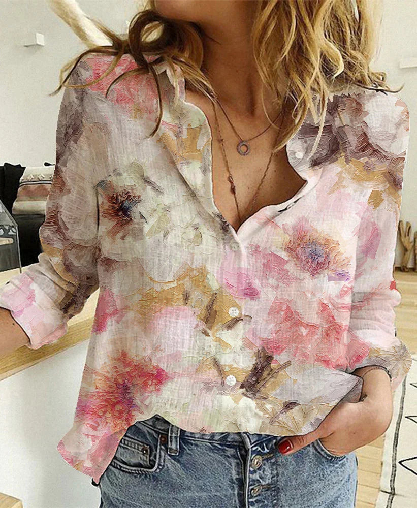 Woman wearing a floral button-up shirt with pink, beige, and brown hues paired with blue jeans indoors