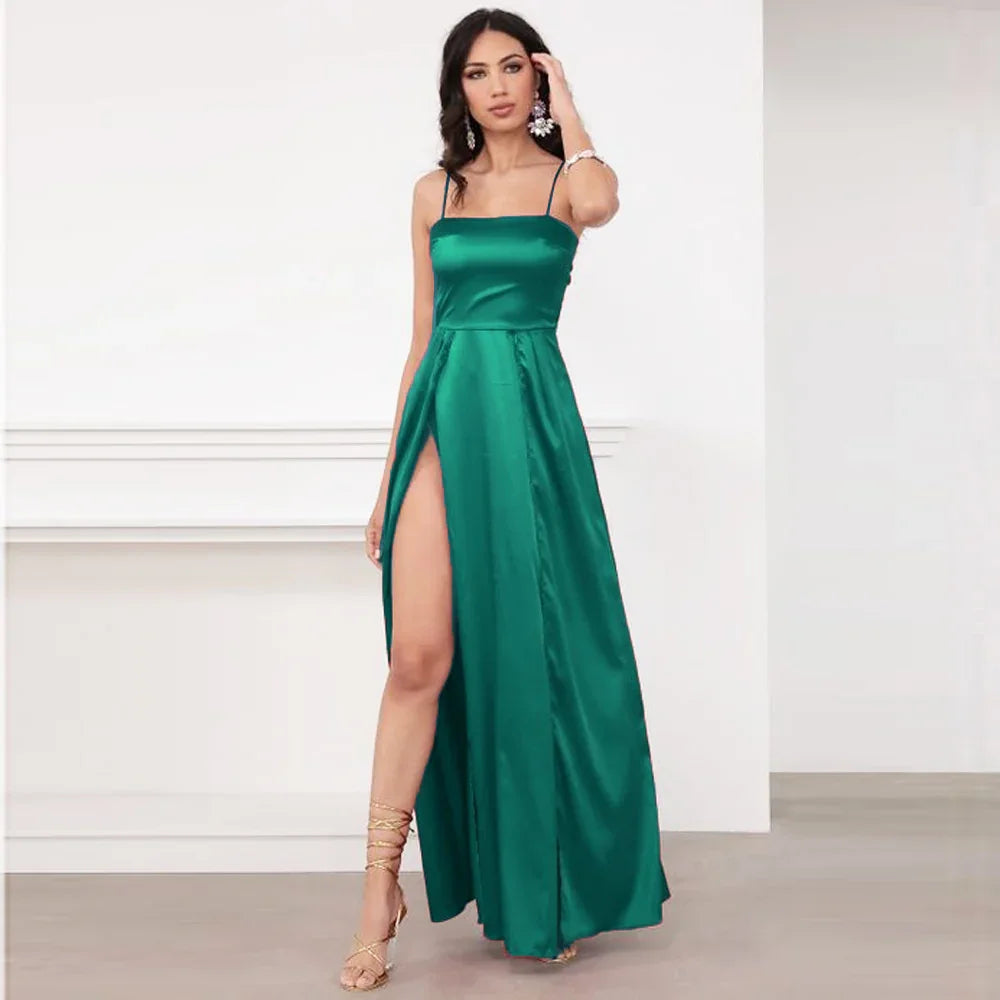 Woman in green satin spaghetti strap evening dress with thigh-high slit in minimal white room