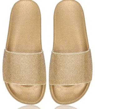 Pair of gold metallic slide sandals with textured wide straps and cushioned footbeds