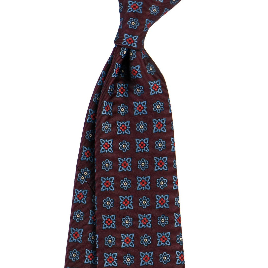 Burgundy tie with blue and red floral geometric pattern on white background