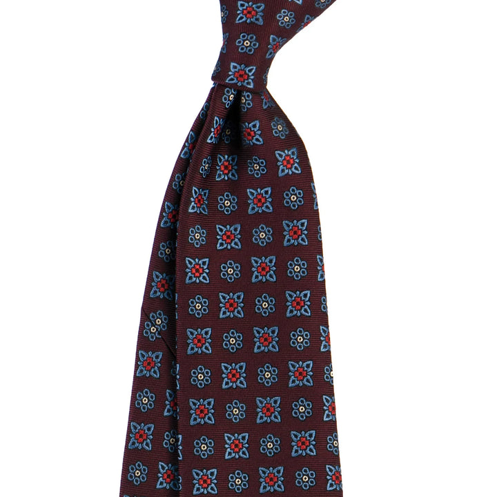 Burgundy tie with blue and red floral geometric pattern on white background