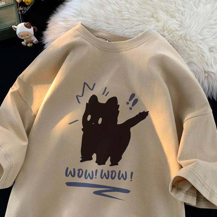 Beige casual t-shirt with black cat graphic and blue text saying wow wow on fluffy surface
