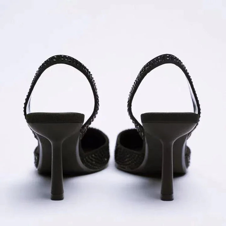 Black high-heeled slingback shoes with rhinestone embellishments on straps, shown from back