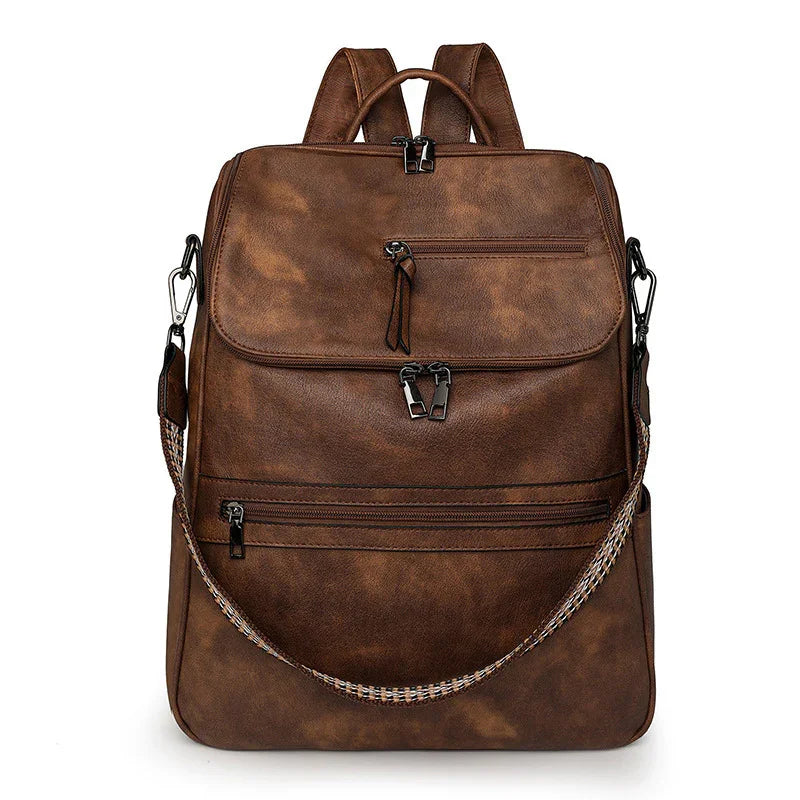 Brown vintage leather backpack with multiple zippered compartments and a detachable patterned shoulder strap