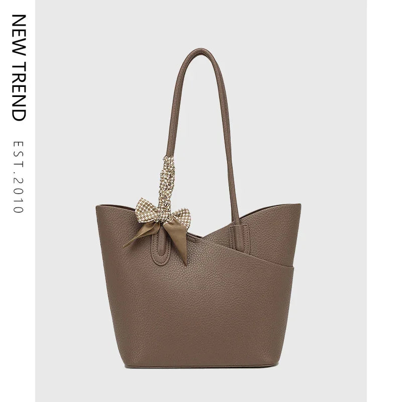 Taupe textured leather tote bag with long handles and decorative bow on one strap