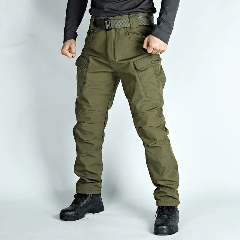 man wearing olive green tactical cargo pants with multiple pockets and black boots on white background