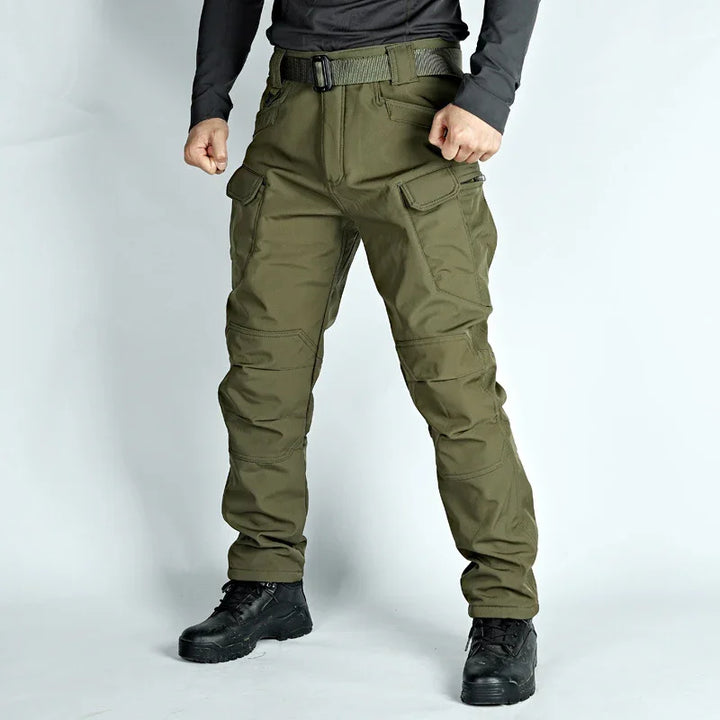 man wearing olive green tactical cargo pants with multiple pockets and black boots on white background