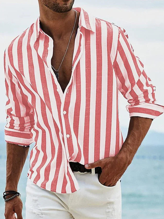 Man wearing red and white vertical striped button-up shirt with rolled sleeves by the beach