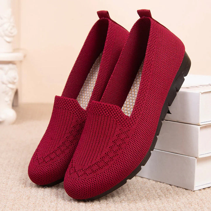 Women’s maroon knit slip-on loafers with black rubber soles on beige carpet