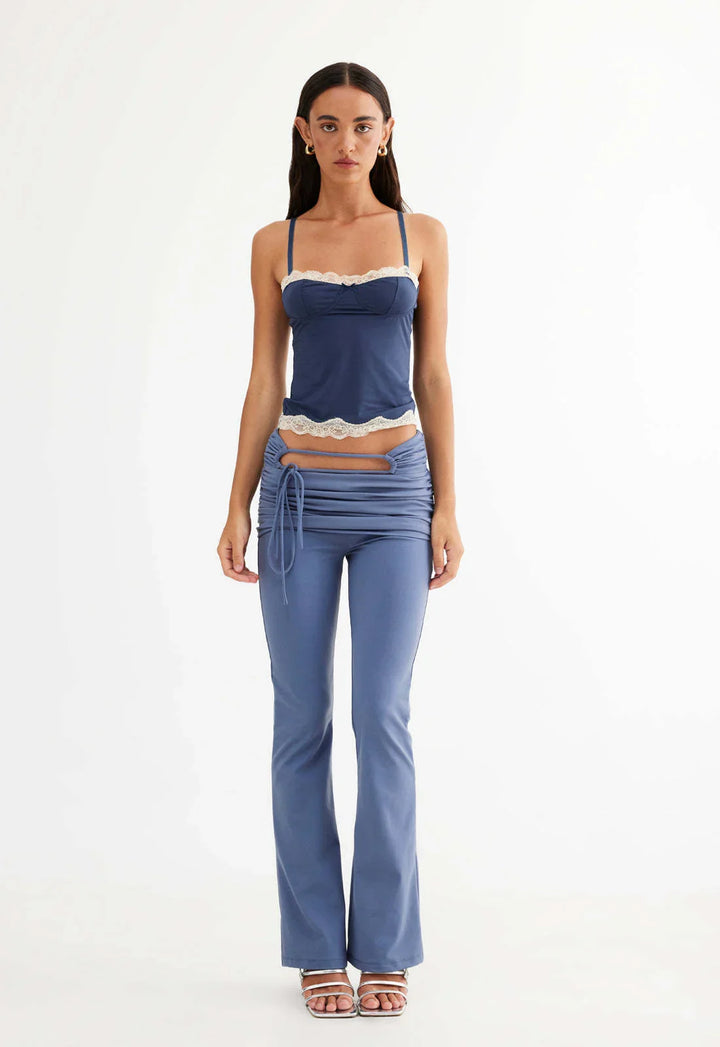 Woman wearing blue lace-trimmed spaghetti strap top and ruched cutout pants with flared legs
