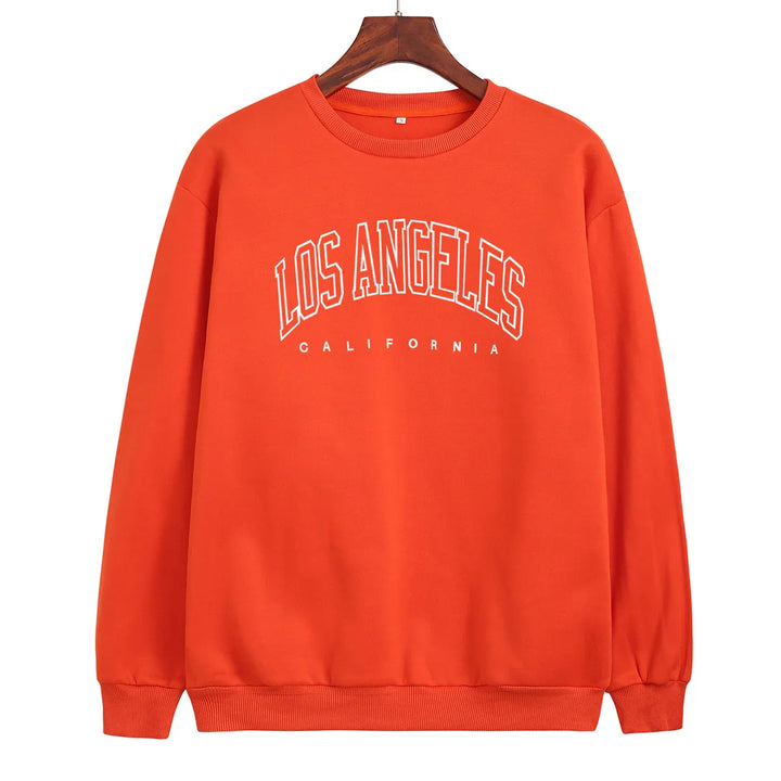 Orange sweatshirt with white Los Angeles California text on front, hanging on wooden hanger