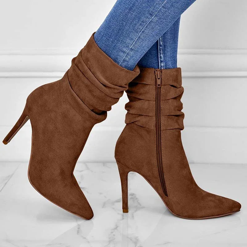 Brown suede high-heeled slouchy ankle boots with side zipper worn with blue skinny jeans on marble floor