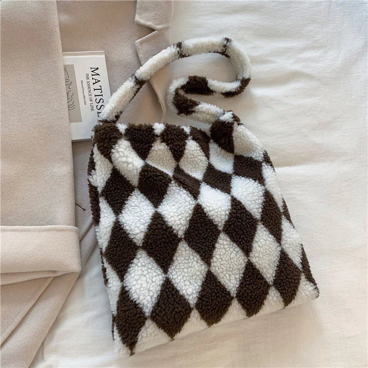 Cozy brown and white checkered fleece handbag with soft texture on beige fabric background