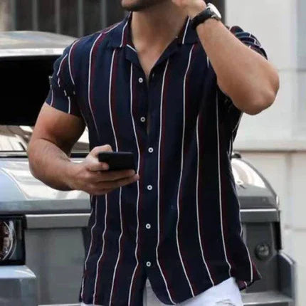Man wearing navy blue short-sleeve button-up shirt with vertical red and white stripes, holding a smartphone outdoors