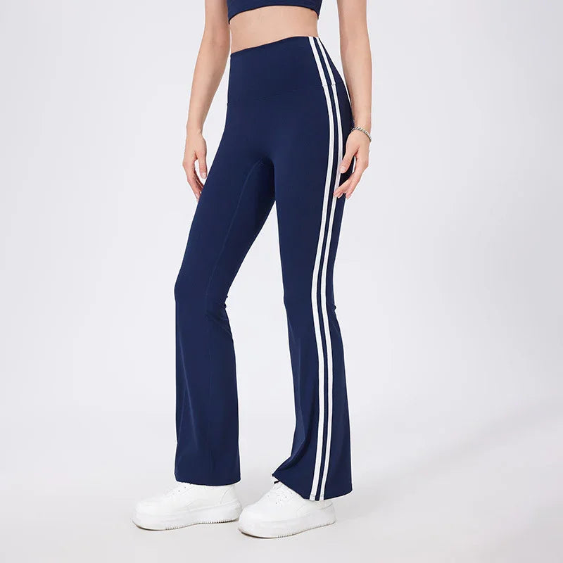 Woman wearing navy blue flared leggings with white side stripes and white sneakers