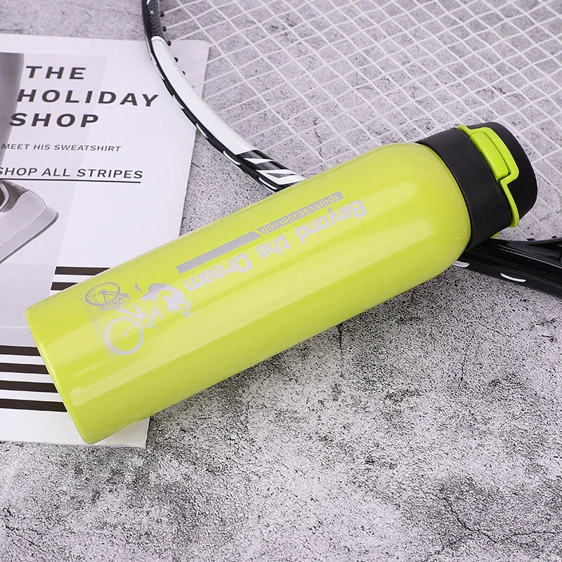 Green sports water bottle with black lid on tennis racket and magazine