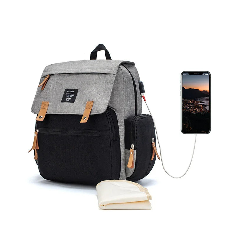 Grey and black backpack with brown zipper pulls and USB charging port connected to smartphone