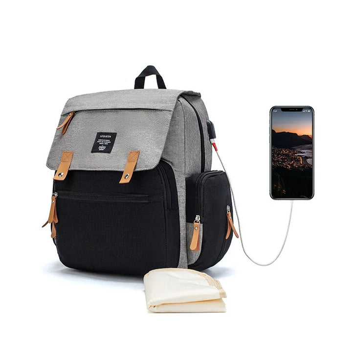 Grey and black backpack with brown zipper pulls and USB charging port connected to smartphone