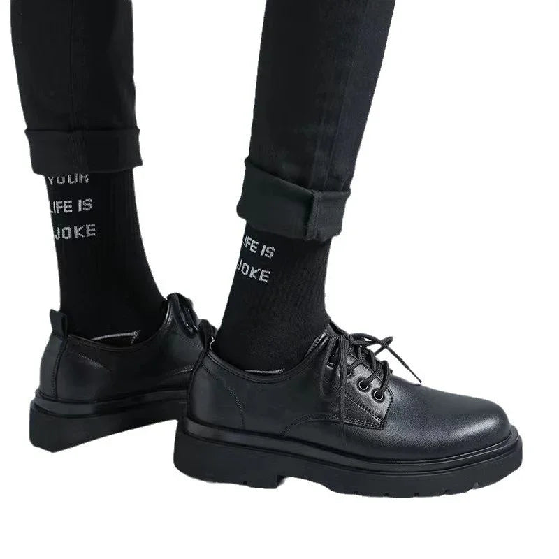 Black leather lace-up shoes worn with black pants and black socks with white text on white background