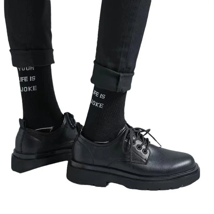 Black leather lace-up shoes worn with black pants and black socks with white text on white background