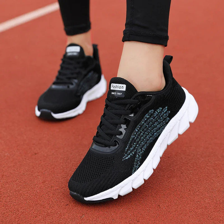 black lightweight running shoes with white soles worn on red track surface