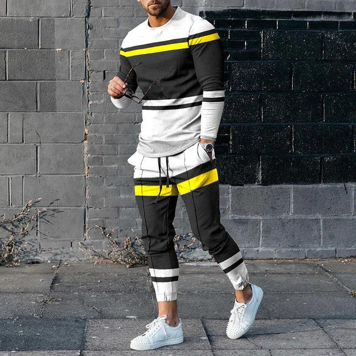 Man wearing black, white, and yellow striped casual tracksuit with white sneakers against gray brick wall
