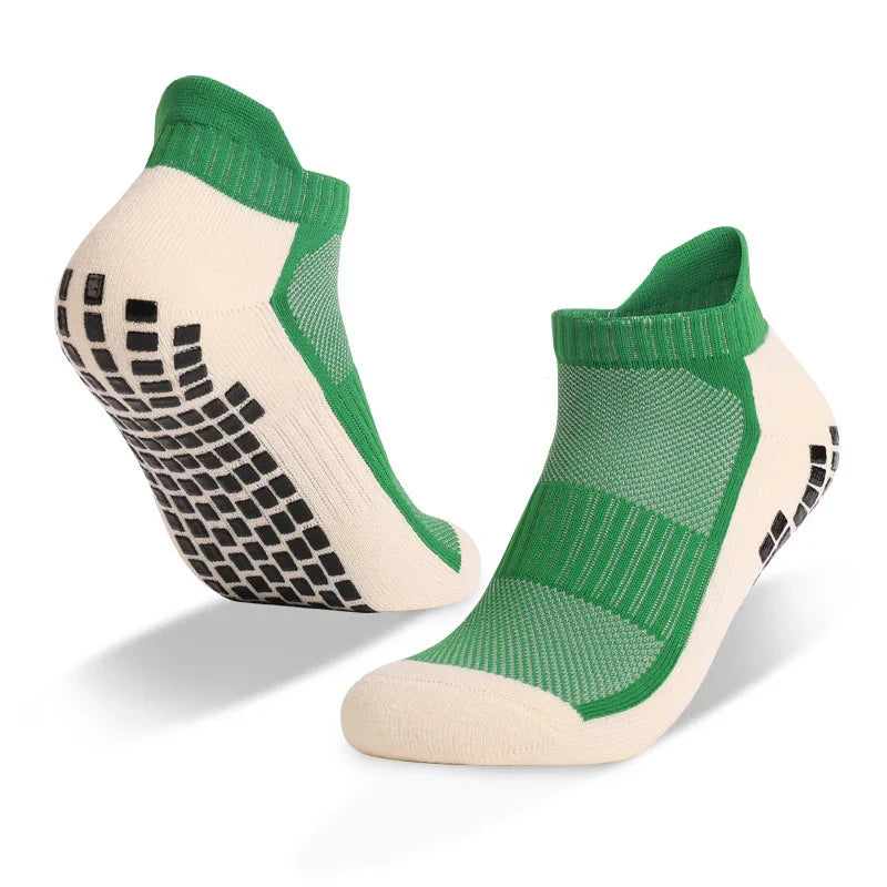Pair of green and beige low-cut non-slip athletic socks with black grip dots on soles