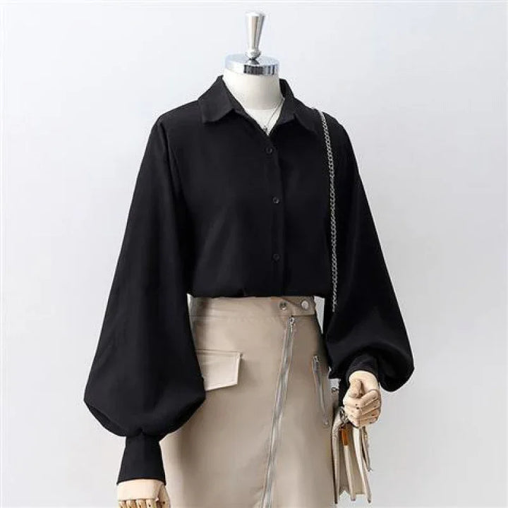 Black button-up blouse with balloon sleeves paired with beige skirt featuring zipper and pocket detail on mannequin